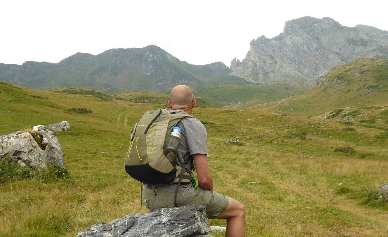 Dr Watt sitting on a rock looking out on a hilly landscape
