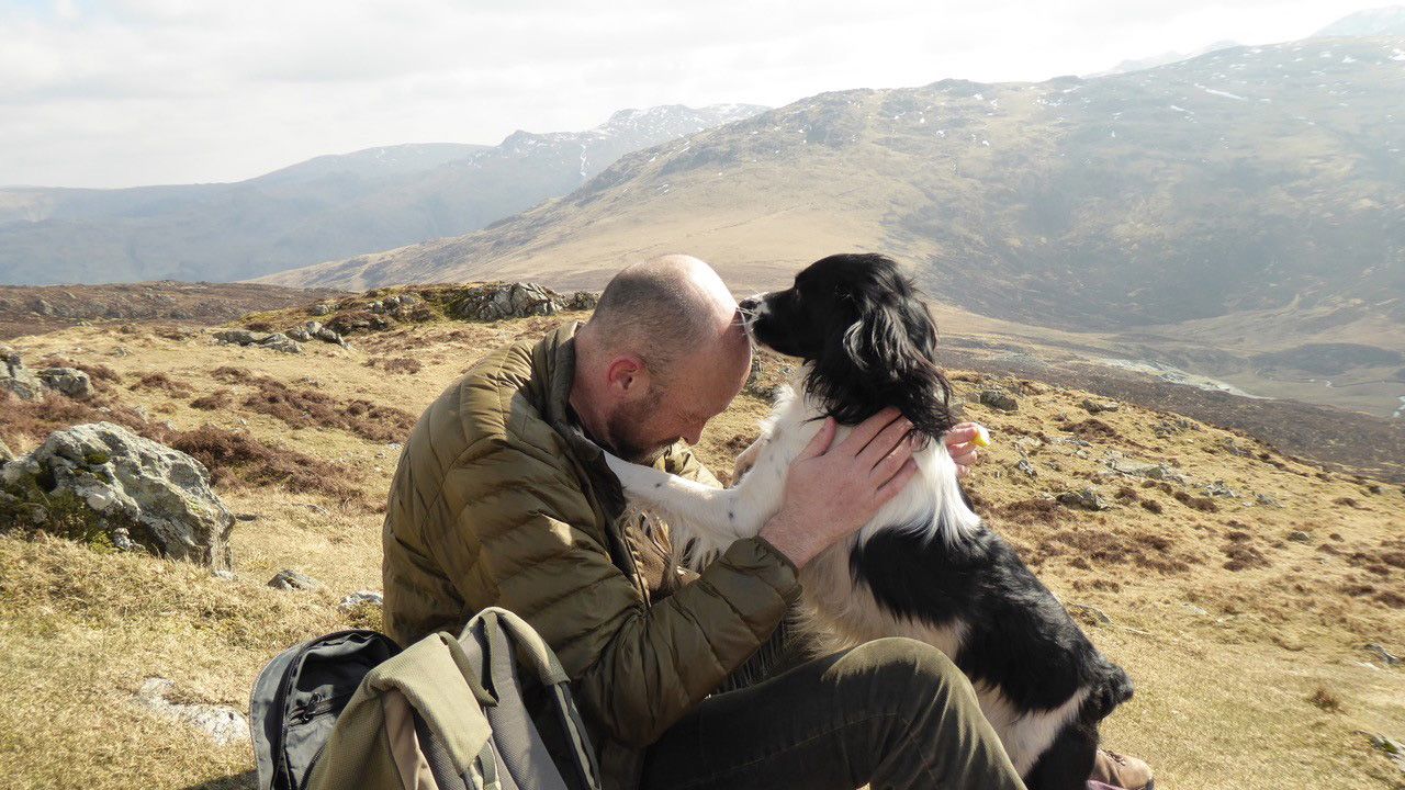 Alastair Watt sits on a hill with his dog Oscar